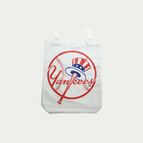 Yankees White tote bag, with Yankees written in red and a baseball bat and ball in the background, the baseball bat has a hat on top of it, the hat is in blue and red.
